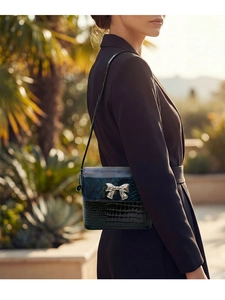 Detail of blue snake and black crocodile texture handbag with silver bow metal clasp