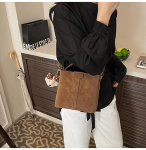 Detailansicht einer braunen Wildleder-Beuteltasche mit einem süßen Teddybär-Anhänger