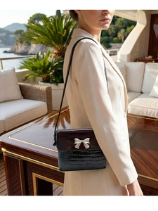 Detail of black crocodile texture bag with silver metallic bow on a luxury terrace