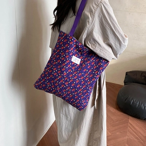 Purple floral canvas tote bag with shoulder strap shown from a side-rear perspective