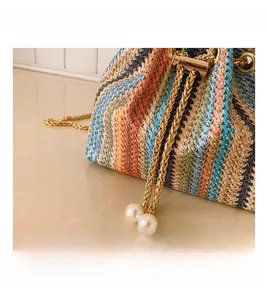 Detail of colorful woven shoulder bag with gold chain drawstring and pearl accents