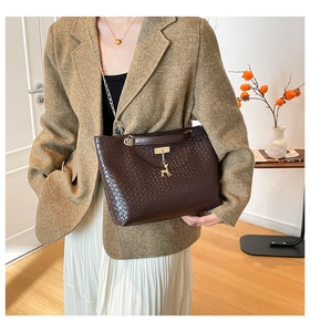 Detail of dark brown woven tote bag featuring gold chain strap and deer pendant charm
