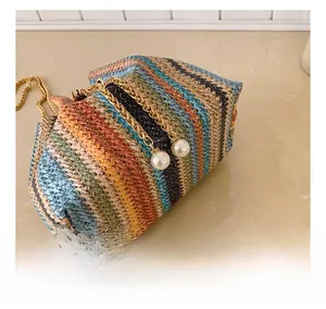 Close-up of woven straw bag with colorful stripes, gold chains, and pearl charms