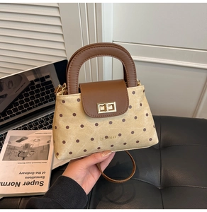 Close-up of a retro polka dot handbag with leather handle and metal turn-lock closure