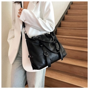 Detail of black PU leather tote bag with silver hardware on a model posing on stairs