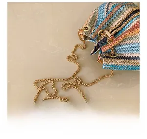 Detail showing the colorful V-shaped woven pattern and golden chain strap of the bucket bag