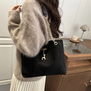 Sac cabas noir rétro avec pendentif cerf doré et bandoulière chaîne sur un mannequin