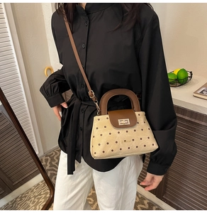 Close-up of retro beige polka dot handbag with brown leather flap and gold twist lock