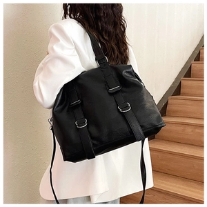 Detail of black PU leather tote bag with silver ring buckles and decorative straps