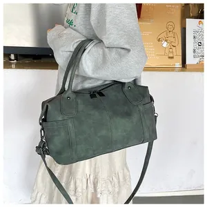 Dettaglio borsa tote verde scuro opaca con tracolla regolabile in un ambiente cafe