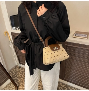 Chic beige polka dot handbag with brown leather flap and adjustable shoulder strap