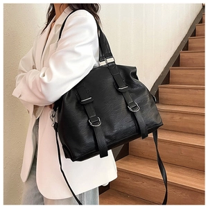 Modern black oversized tote bag with silver buckle and wide strap on model stairs