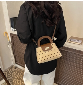 Rear view of a model wearing the beige polka dot handbag with brown leather straps