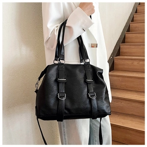Detail of black pebbled PU leather tote bag with silver hardware on a white blazer model