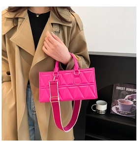 Detail of pink quilted handbag with wide shoulder strap and gold-tone metal hardware