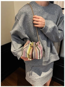Detail of colorful woven mini bucket bag with gold chain strap and pearl drawstring