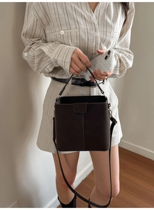 Detailed view of dark matte bucket bag showing clean stitching and magnetic flap closure