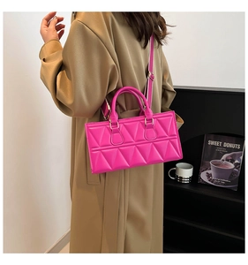 Detail of rose pink quilted crossbody bag with wide strap on a khaki trench coat