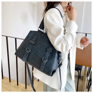 Deep blue faux leather tote bag detail with metal ring buckles and adjustable shoulder strap