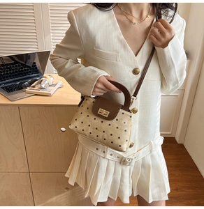 Detailed view of polka dot crossbody bag with golden square lock and leather handle