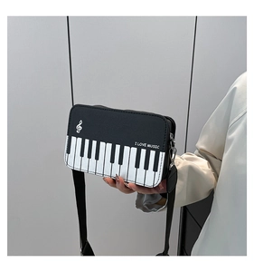 Close-up of piano key design and music note logo on a black and white leather crossbody bag