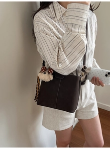 Details der dunkelbraunen Vintage-Umhängetasche mit Bärenanhänger und Seidenschal