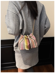 Detailed shot of rainbow woven bucket bag with pearl pendants and gold chain strap
