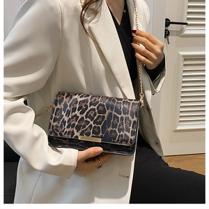 Detail of leopard print crossbody bag with gold chain strap styled on a white blazer