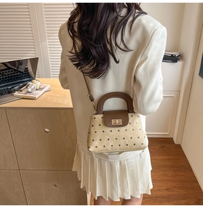 Close-up of retro polka dot handbag with vintage gold buckle and leather strap details