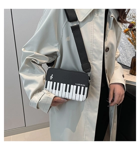 Detail view of piano key crossbody bag featuring I Love Music slogan and wide strap