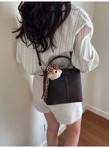 Detailansicht der dunkelbraunen Wildleder-Tasche mit Bärenanhänger und Seidenschal-Deko