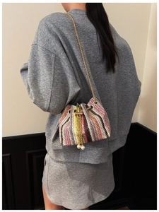Detail view of rainbow striped woven bucket bag with elegant pearl charms and gold chain