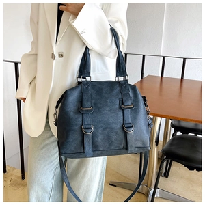 Detail of dark blue vintage textured handbag with metal D-rings and double handles