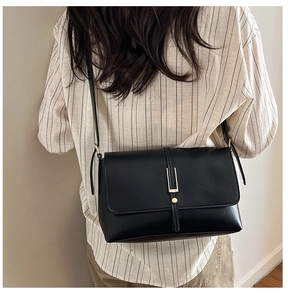 Détail d'un sac bandoulière noir avec fermoir métallique doré et fine bandoulière