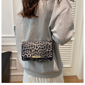 Side view of leopard print crossbody bag with gold chain strap worn by a model