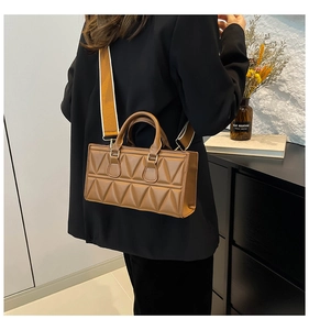 Close-up of brown triangular quilted handbag with orange wide woven shoulder strap