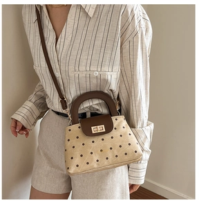 Detail of vintage polka dot handbag featuring contrast leather handle and golden twist lock