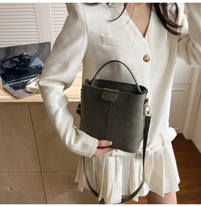 Detail view of a vintage dark green bucket bag with gold hardware and matte leather texture