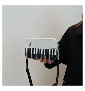 Detail of piano keyboard pattern and 'I LOVE MUSIC' print on a black and white crossbody bag