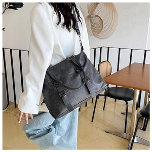 Modern black PU leather tote bag with metal ring buckles and adjustable strap on a model