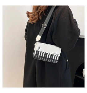 Detail showing music-themed crossbody bag with piano key print and adjustable strap