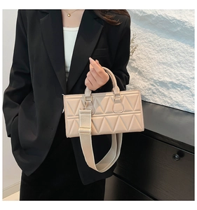 Detail of a beige triangle quilted handbag with a wide adjustable shoulder strap