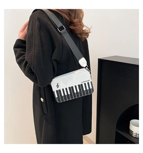 Side view of white leather crossbody bag featuring piano keys and music note design