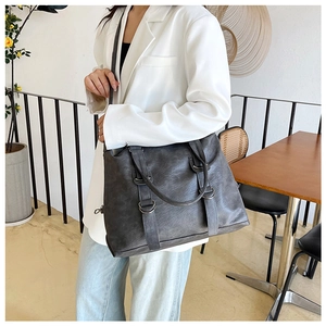 Close-up of charcoal grey faux leather tote bag showing textured surface and metal rings