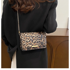 Detailed view of the leopard print crossbody bag with gold chain strap on a model