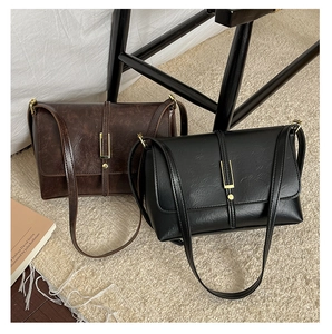 Détail de sacs bandoulière en cuir mat vintage marron et noir avec fermoirs dorés élégants