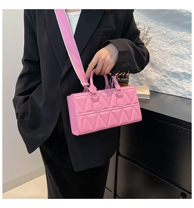 Detailed view of pink quilted handbag with wide canvas strap on model wearing black suit