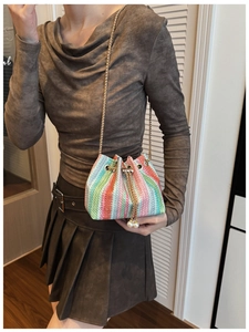 Close-up of rainbow woven bucket bag with pearl charms and gold chain strap detail