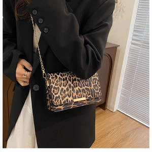 Minimalist leopard print crossbody bag with gold chain strap worn over a black blazer