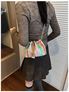 Detail of colorful woven bucket bag with gold chain strap and pearl drawstring tassels